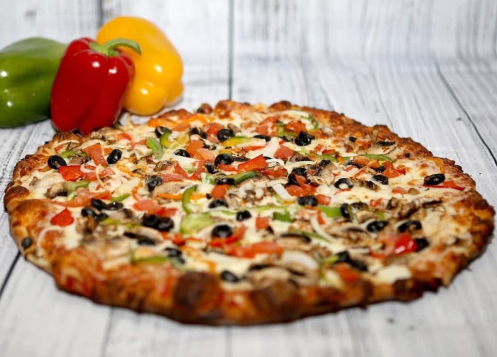 Vegetable pizza with bell peppers, mushrooms, olives, and melted cheese on a wooden board